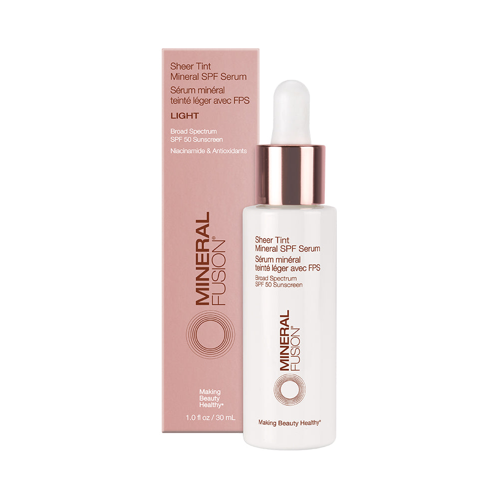 A bottle of Mineral Fusion Sheer Tint Mineral SPF Serum with its packaging box. The bottle is white with a pink dropper, and the box is pink with product information.